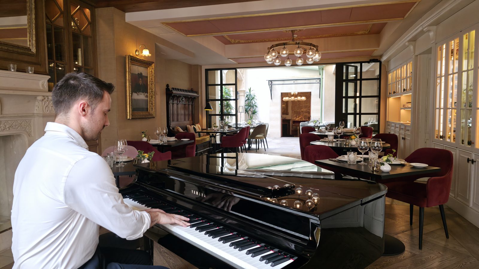 Michal al piano en El Patio de Glòria, con las mesas del restaurante al fondo