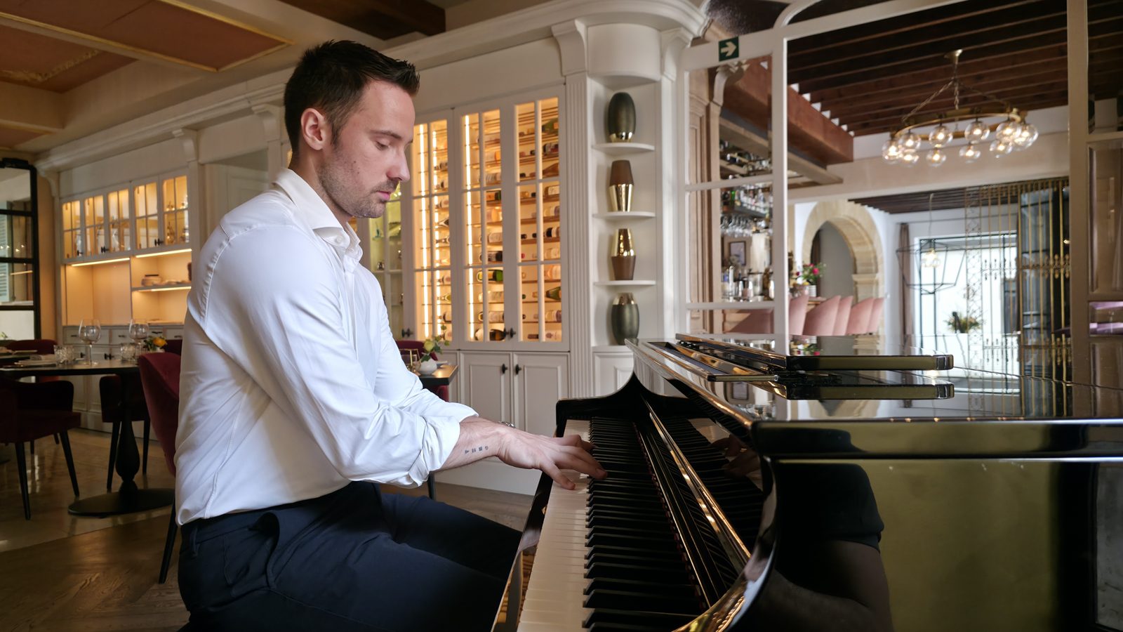 Michal tocando el piano de cola junto a la vinoteca del Patio
